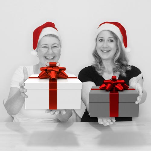 Susanne und Britta mit Nikokausmützen halten jeweils ein Geschenk mit roter Schelife in die Kamera.